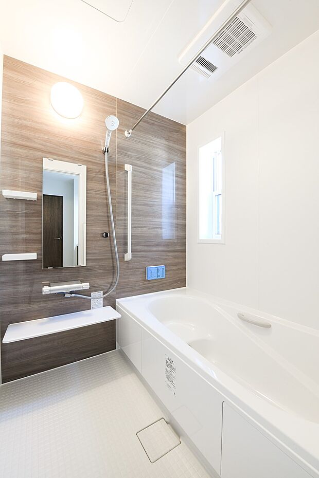 【浴室】木目調の壁面がアクセントになった、清潔感あるホワイトを基調とした空間。温かみが感じられ、ほっとできる色合いは、のんびりくつろぐ浴室にぴったりです。（19号棟）