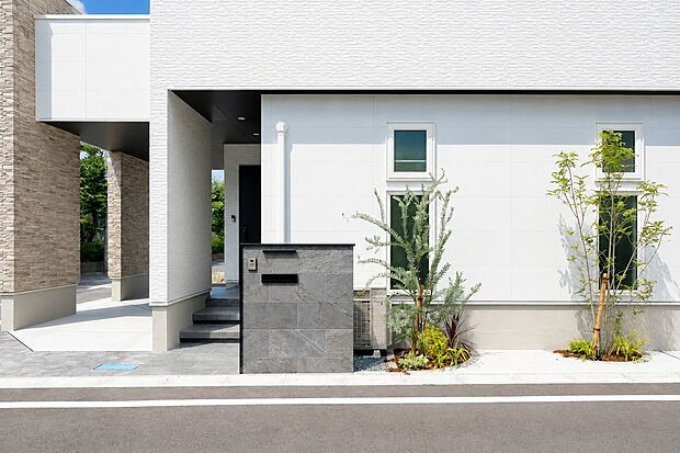 【外観】石目調の門柱と植栽が調和した外構デザイン。建物との一体感を大切にしながら、上質感とプライバシー性を兼ね備えたアプローチ空間を実現しました。