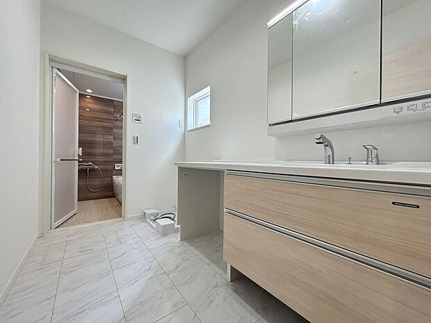 【洗面脱衣室】洗練されたデザインと清潔感のある空間で、タオルや化粧品を効率的に収納できます。3面鏡の鏡の裏には便利な収納が備わっており、毎日の身支度がスムーズに行えます。