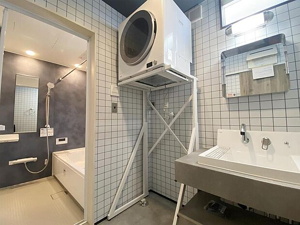 【家事効率にも配慮】LIXILのカスタムバニティと耐水メラミンカウンターを採用した、上質感あふれる洗面化粧室。乾太くんや大容量ボウル、くるくる水栓を備え、家事効率にも配慮。ダルトンとハモサの照明が空間を美しく演出します。