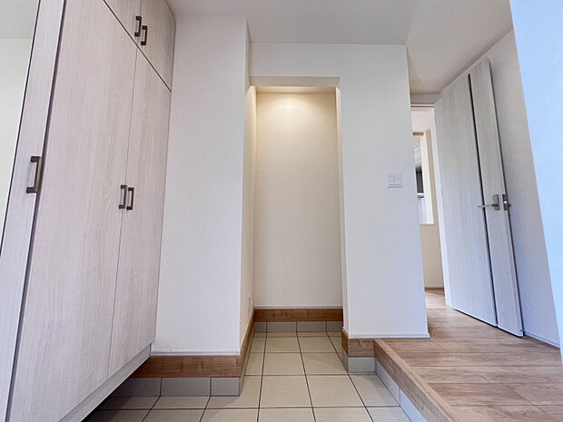 【1号棟　玄関収納】　クロスや建具を白で統一した清潔感のある玄関です。大容量のシューズボックスのほか、玄関土間収納も設けています。