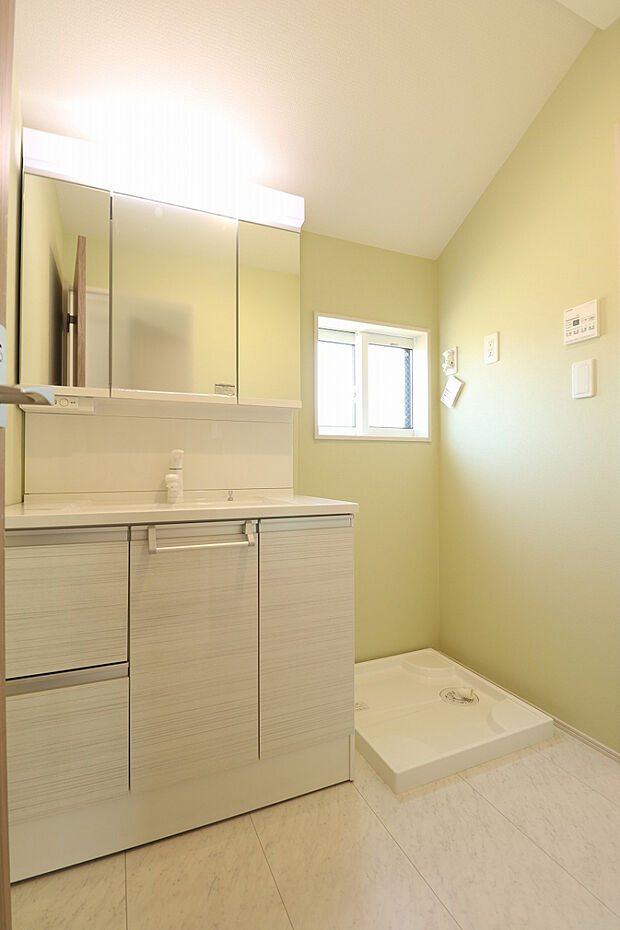 【【1号棟/洗面化粧台】】パステルカラーのアクセントクロスを施した清潔感のある洗面室です。洗面台は洗面ボウル下、三面鏡裏に収納スペースがあります。