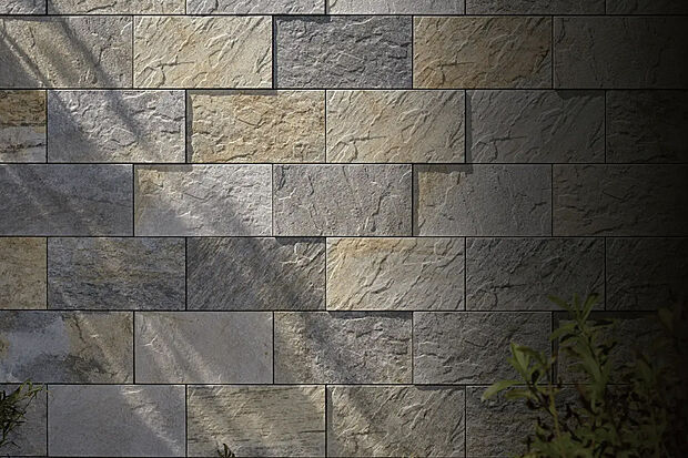 【ストーンタイプタイル外壁】昼間の太陽や夜間のライトなどが外壁を照らすことで陰影ある表情を演出。壁面の見映えが大きく変わります。意匠性を高めるメリットに加えて、汚れに強く耐久性に優れた品質の高いタイルです。（参考写真）