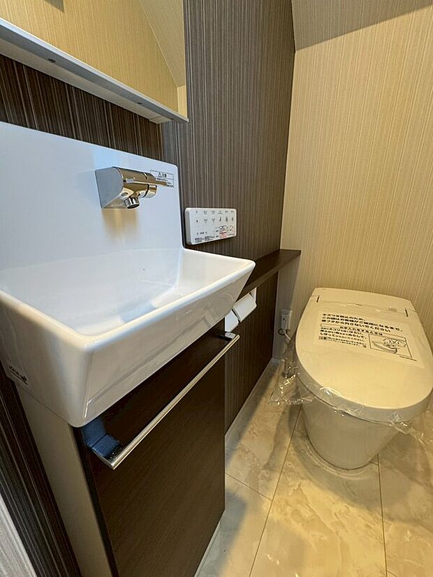 【タンクレストイレ】メーカー：リクシル　タンクレス、便器はフチのないデザインでお掃除ラクラク！手洗い器上部にはトイレットペーパーやお掃除用具をきれいに収納でき、スッキリとした空間に。自動でフタが開き、使い勝手も抜群！