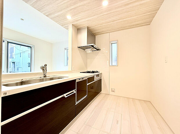 【キッチン】空間にメリハリを演出するダークカラーのシステムキッチン。カウンター下部の収納は、奥にしまった大型の鍋類なども取り出しやすいスライド式です。