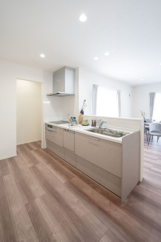 【1階キッチン/A号地】キッチンコンロは立ち上がり部分が少なくお手入れがしやすいIHヒーター。ウォークインタイプのパントリーは床面まで無駄なく使うことができ、食材のストックや調理家電などが収まります。