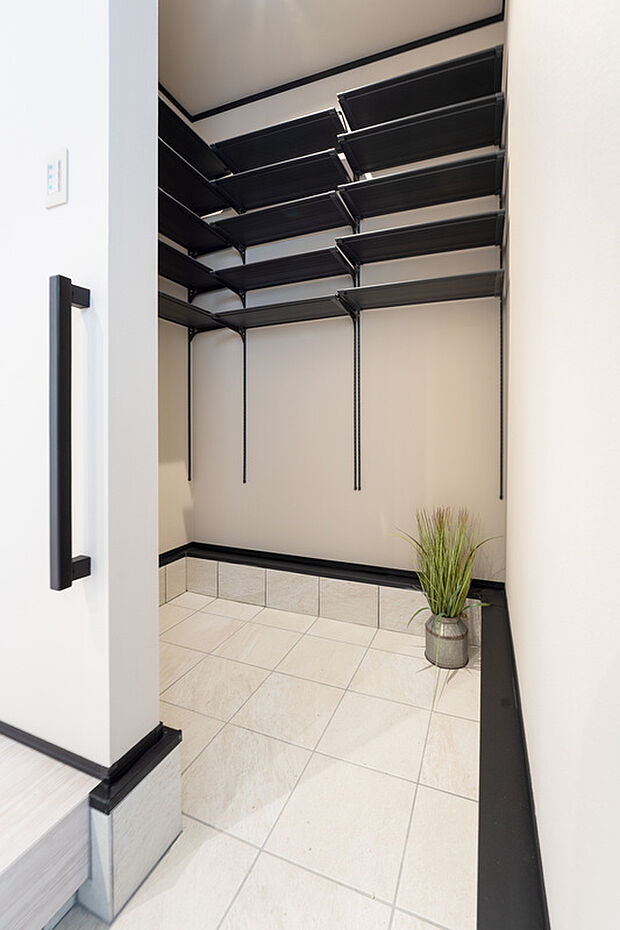 【【1階玄関土間収納/B号地モデルハウス】】土間収納は奥行きを設けてゆとりあるサイズに。履物を脱ぐ前に、ベビーカーや外使いするアウトドアグッズをさっと収納でき便利です。お気に入りの履物もオープンシェルフでオシャレに収納できます。