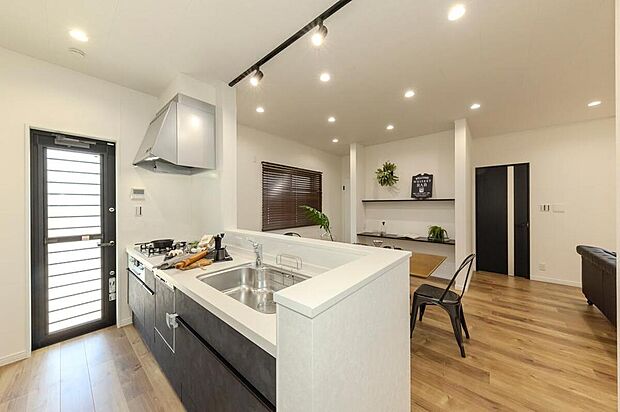 【【キッチン/当社施工例】】質感のあるキッチンパネルが高級感のある印象。開放感はそのままに、調理中の手元を隠せる腰壁を設け、生活感を抑えられるよう配慮しました。