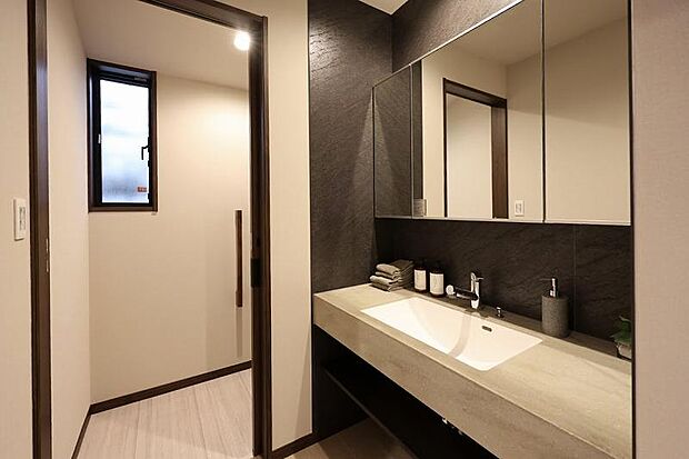 【洗面化粧台】現地(2025年7月)撮影 脱衣所とは独立した洗面室。来客時やリビングとつながった位置に設置しても違和感のないミサワホームオリジナルの洗面化粧台です。 左側のドアの奥にはトイレがあります。