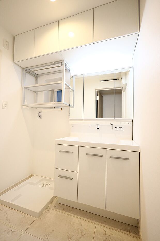 【【洗面室/2号棟】】上部の吊り棚や洗面化粧台下、3面鏡裏など収納スペースが充実しています。タオルを収納したり、洗濯洗剤、掃除用具などのストックをしまっておくことができます。洗面化粧台の水栓は洗髪や洗顔の際に使い勝手のいいシャワータイプです。※未入居住宅