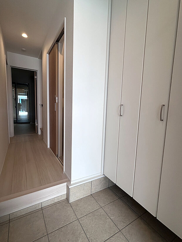 【【1階玄関】】玄関西側の壁一面には、天井までの大容量のSCLが設置されています。吊戸式で床面まで無駄なく利用でき、可動棚にご家族皆さまの靴をまとめて保管いただけます。/2025年3月撮影