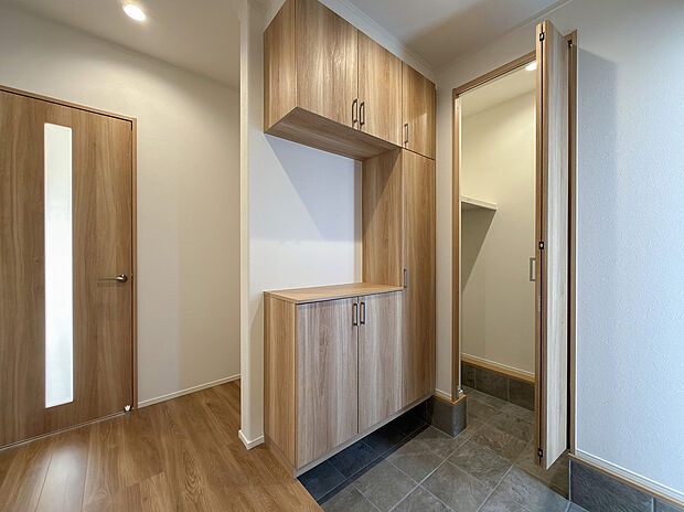 【1階玄関/A号地モデルハウス】土間収納は土足のままで出入りができ、来客時は扉を閉めることで生活感をカット。玄関収納+土間収納により、靴やベビーカー、雨具などのお出掛け用品がスッキリ収まります。