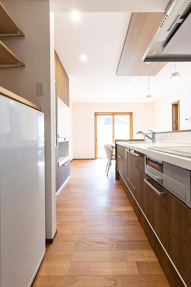 【キッチン】キッチンのコンロ向かいにはラックと冷凍庫が置ける収納スペースを設置。ストック品や大容量の冷凍食品もしまいやすいです。