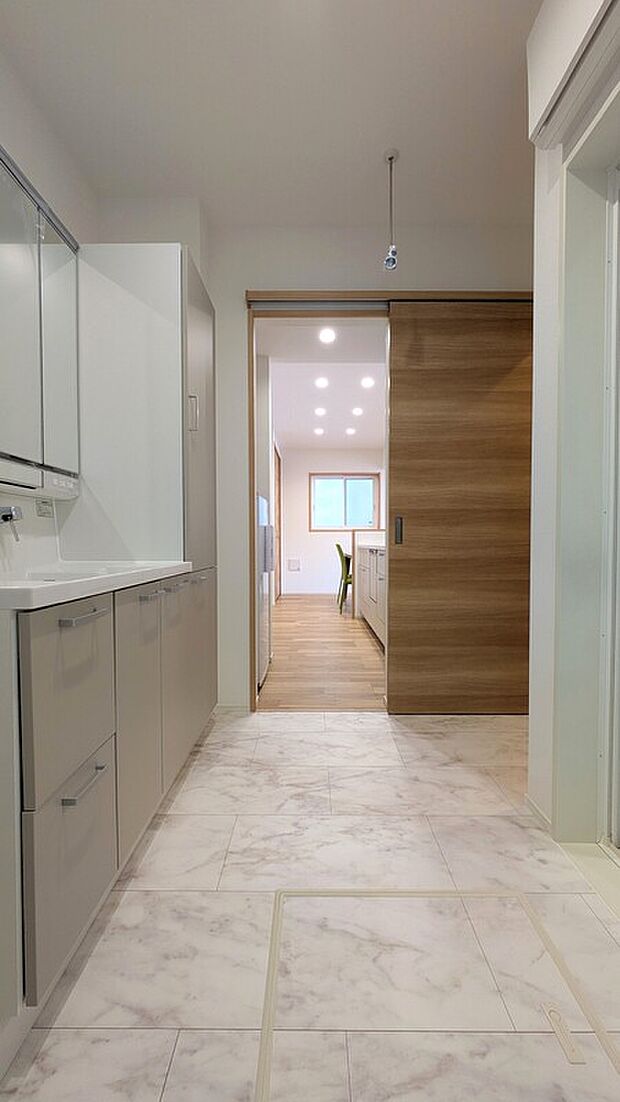 【NO.3　洗面室】洗面室とキッチンが一直線につながる効率的な家事動線。食事の準備をしながら洗濯など、同時進行の多い家事の移動負担を軽減し、毎日の暮らしをスムーズにサポートします。