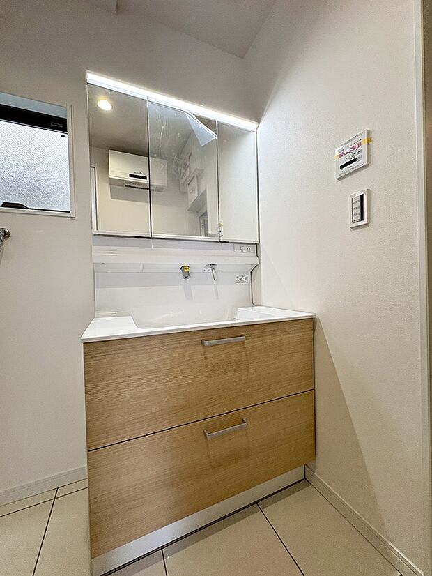 【【A号棟洗面所】】フラットな三面鏡が採用された洗面化粧台が設置されています。水栓は上方吐水タイプで、水栓周りに水が溜まりにくい仕様です。