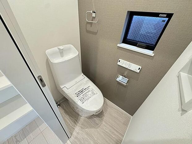 【【トイレ】】シックなクロスが映える上質空間。温水洗浄便座と節水型トイレで、毎日の生活を快適＆エコに。扉を閉めればすっきり壁面と一体化し、必要な物を手の届く場所に。