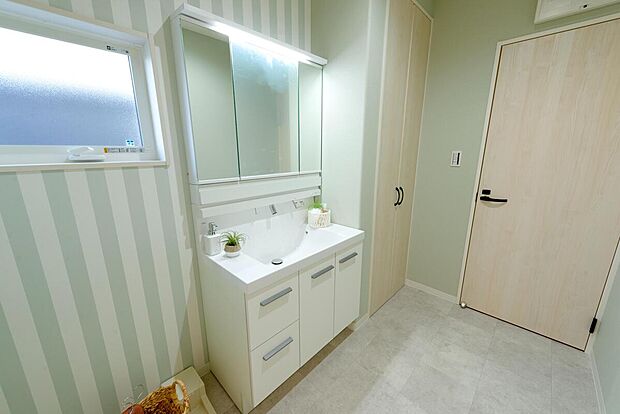 【1階ランドリールーム/B号地モデルハウス】キッチンからショートカットで出入りができる家事ラク動線。グリーンのクロスが爽やかな印象です。ホスクリーンを2組備え、洗濯物を洗う→干すが1か所で完結します。