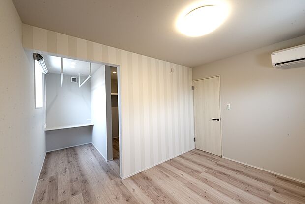 【【2階約8.3帖洋室/C’号地モデルハウス】】約2.3帖のWICを備えた広々とした洋室。WICへの出入り口はあえて扉を設けず、出入りがスムーズです。WIC近くには室内干しなどに便利なホスクリーンを2連で配置しています。カウンタースペースはWICから近いため、パウダースペースとしても便利。コンセントがあるため、美容家電もお使いいただけます。