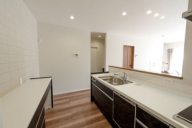 【【1階キッチン/A号地モデルハウス】】キッチンは調理中でもリビングやダイニングのご家族とコミュニケーションがとりやすい対面式。背面のカップボードは統一感あるデザインで、調理スペースや家電置き場などにご活用いただけます。シンク横から水回りがすぐで、家事のマルチタスクが捗りそうです。