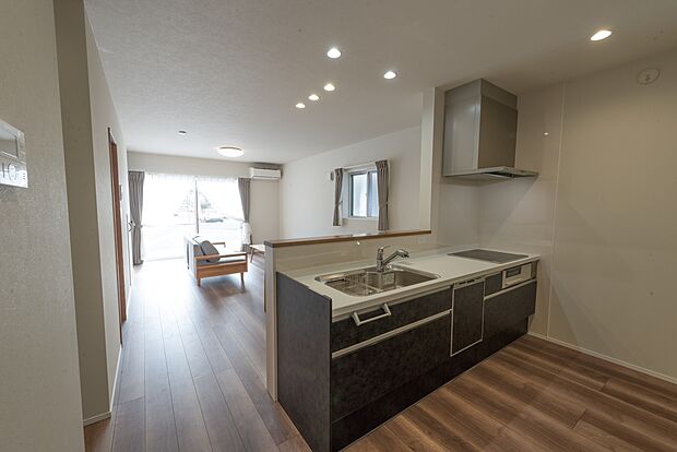 【【1階LDK約17.8帖/A号地モデルハウス】】リビングの南窓からの陽だまりが心地よいLDKは、ダウンライトやフロアの木目がより伸びやかな空間を演出。キッチン、ダイニング、リビングをストレートに配置し、1階のどこにいても一体感を感じられるI型です。