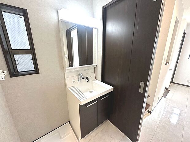 【【アーバンポート施工例】洗面化粧台】大きな三面鏡と併せてリネン類等、たっぷりしまえる収納力を備えています。