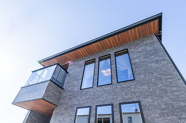 【当社施工例/外観】
グレーの石目調を基調とした外壁が印象的な邸宅。木目の軒天がアクセントとなり、洗練された雰囲気を演出します。