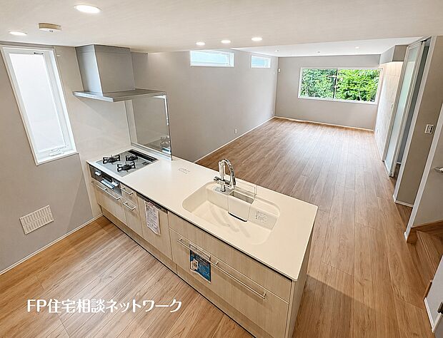 【リビング】家族の会話が弾む、開放感あふれる対面式キッチンを備えたLDKです。窓から自然光がたっぷりと降り注ぎ、木の温もりを感じるフローリングが心地よい、明るく快適な団らん空間です。