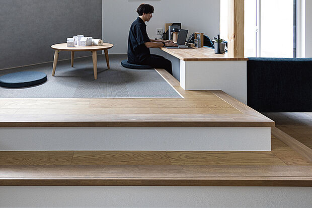 【【家族の気配を自然に感じるステージリビング】】段差で空間をゾーニングすることで家族の気配を感じながら、趣味や仕事、勉強などの自分時間を楽しむ独立性を実現します。(23号棟/2025年9月撮影)