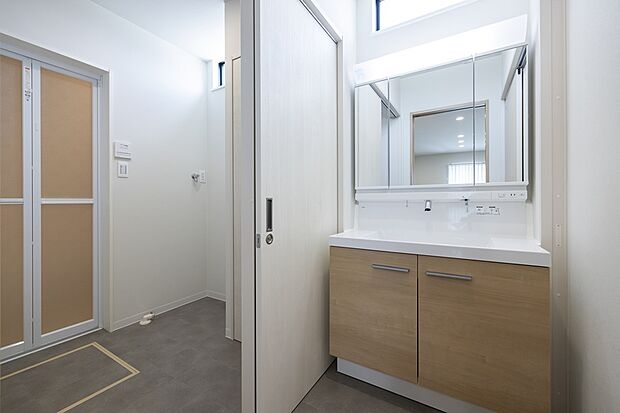 【【1階洗面所・脱衣所/2号地モデルハウス】】キッチン背面に水回りを集約。洗面所はトイレに隣接し、洗面所・脱衣所は扉を閉めると独立空間に早変わりします。ご家族が入浴中でも利用しやすく、家事が捗り機能的です。