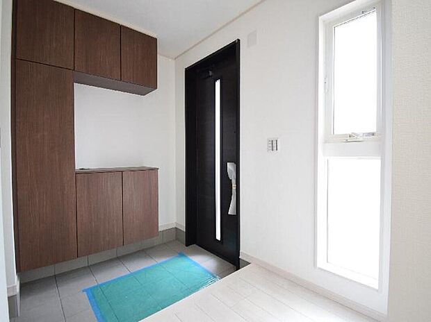 【2号棟　玄関】
窓からの光が明るく照らす玄関で訪れる人を優しく迎え入れます。
大容量のシューズボックスは約60足分の靴が収納可能。