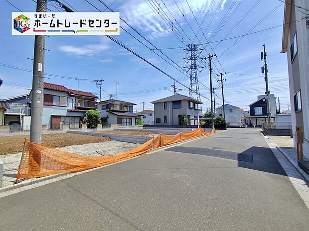 【分譲地の前面道路と区画】6.0m舗装公道(南西側)に面した整地済みの分譲区画。周囲に既存住宅が並びます。