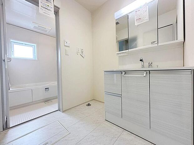 【洗面台・洗面所】白を基調とした高級感のあるサニタリースペース。収納たっぷりの三面鏡に陽の光差し込む明るい空間で、毎日の身支度も気持ち良くお使い頂けます。