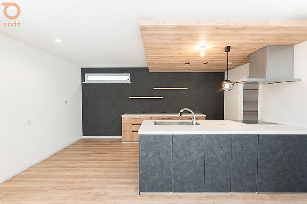 【ondo建物プラン例/LDK】木目の下がり天井とブラックのアクセントが映えるキッチン。落ち着きのあるデザインの中で、料理をしながら家族との会話も自然と生まれる空間です。