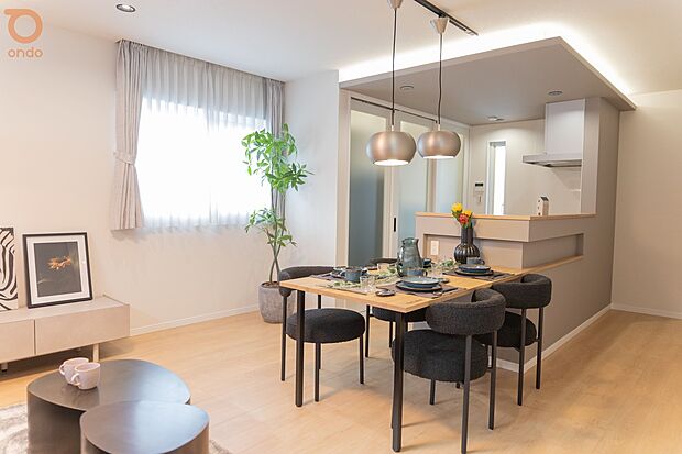 【ondo建物プラン例/LDK】やわらかな日差しが届く明るいLDK。淡い木目の床と落ち着いたトーンのキッチンが調和し、折り上げ天井の間接照明が空間に上品なアクセントを添えています。