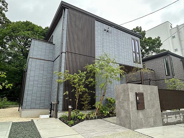 【外観【2号地】（2025年8月撮影）】自然豊かな周辺環境に溶け込むタイル外壁と化粧格子の組み合わせ