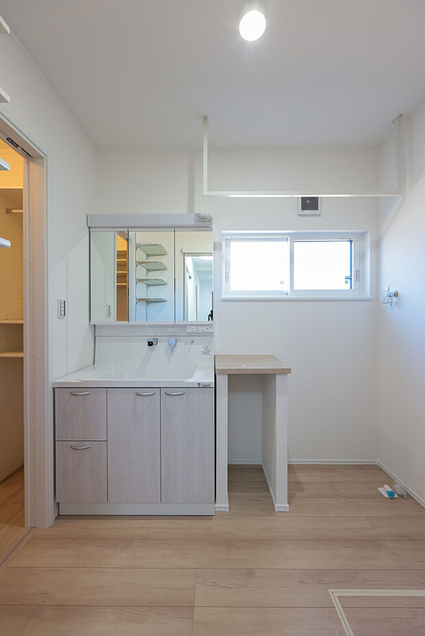 【4号棟　洗面所】「洗う・干す・畳む」が1ヶ所で完結する家事ラク洗面室。室内物干しと便利な作業台を完備し、天候を気にせず洗濯が捗ります。隣接する収納への動線もスムーズで、忙しい毎日の家事時間をゆとりの時間へ変えます。