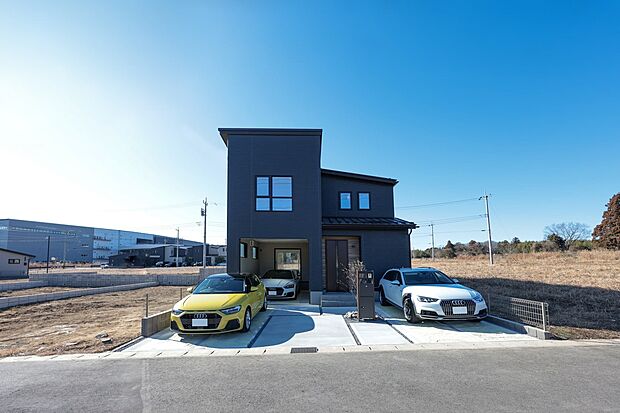 【1号棟】洗練されたネイビーの外壁とシャープな片流れ屋根が目を引くモダンな住まい。愛車を引き立てるビルトインガレージを備え、青空に映えるスタイリッシュな佇まいが暮らしの質を高めます。