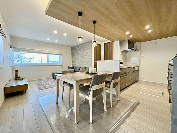 キッチンを中心に家族の会話も弾む間取り。対面キッチンでダイニングともつながり、配膳や片付けもスムーズです。木目調の下がり天井がアクセントとなり、心地よい空間を演出します。