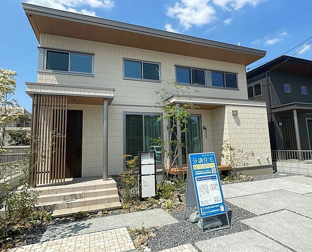 ベージュのジオマイト外壁に、木目調の軒天や格子がアクセント。重厚感とナチュラルさが調和した、街並みに映える美しいデザインです。