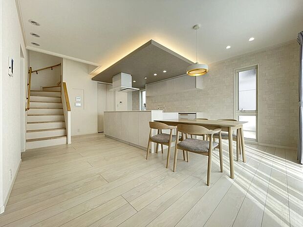 自然光が心地よい開放的なダイニングキッチン。グレーの折り下げ天井と間接照明が、白基調の空間に奥行きと上質さをプラスします。最高級キッチン「CENTRO」を囲み、家族の会話が自然と弾む温かな住まいです。