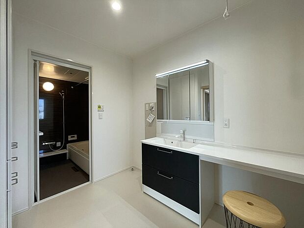 【洗面室】ゆとりのある洗面脱衣室には、メイクや洗濯物の整理に便利なワイドカウンターを採用。キッチンからの動線もスムーズで、家事効率をぐんと高めてくれます。落ち着いたトーンの浴室へと続く、清潔感あふれる空間です。