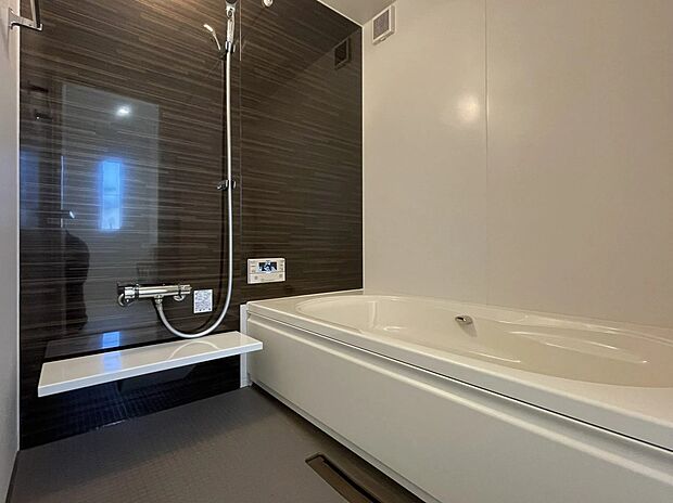 【浴室】シックなアクセントパネルが落ち着きを演出する、上質なバスルーム。ゆったりとした浴槽は、一日の疲れをやさしく解きほぐしてくれます。浴室乾燥機も完備し、雨の日のお洗濯も安心な、機能性にも優れた空間です。