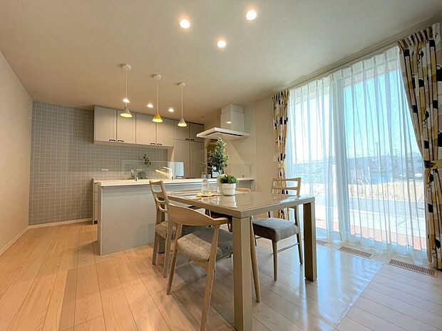 【リビング】やわらかな色調でまとめたキッチンは、リビングやダイニングとつながる開放的な設計。パントリーやスムーズな動線で家事効率もアップし、家族の気配を感じながら過ごせる心地よい空間です。