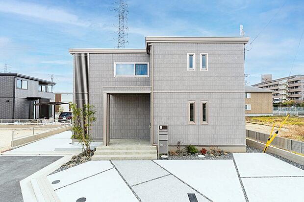 グレーの落ち着いた外壁とシンプルな四角いフォルムが調和した外観。駐車スペースも整備され、心地よい住まいです。