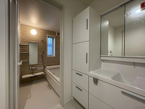 【洗面所】空間を明るく広々とした洗面スペースは白で統一。隣接するバスルームには温かみのある木目調のアクセントパネルを配しました。、