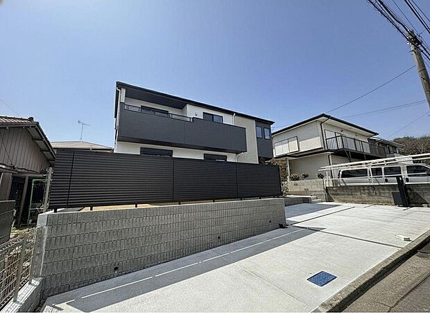 【前面道路含む現地写真】青空に映えるモダンな外観が魅力です。ゆとりの駐車スペースは、家族の車はもちろん、来客時も安心。新しい暮らしがここから始まります。