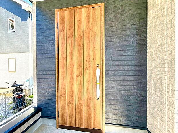 【玄関】木の温もりを感じる玄関ドアが、家族の帰りを優しく迎えます。落ち着いた色合いの外壁と調和し、洗練された印象を与えます。