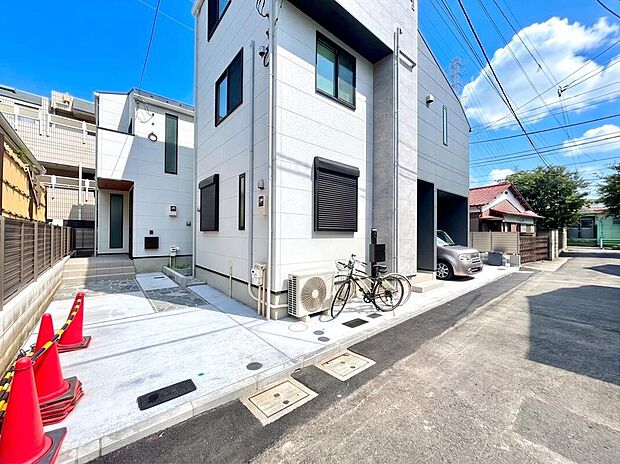 【前面道路含む現地写真】自転車スペースや、すっきりとしたアプローチを設けたスマートな外構設計。敷地を有効に活用し、住まう人の快適な使い勝手と美しさを両立させています。