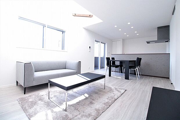 リビング　A号棟　同仕様写真
■上部に吹抜を設け、2つの窓から取り入れる光がLDKを明るく照らしてくれます。空気を汚さず、ふく射熱で足元からポカポカと暖まる床暖房付き。