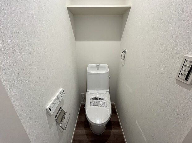 【トイレ　B号棟現地写真】スマホを持っていればドアハンドルのボタンを押すだけで施解錠でき、さらにアプリから施錠履歴も確認可能。
また、ドアハンドルはボタンが低い位置にあるため、小さなお子様や車椅子の方にも操作がしやすく、握る際に手になじむ丸みのあるグリップ形状です。